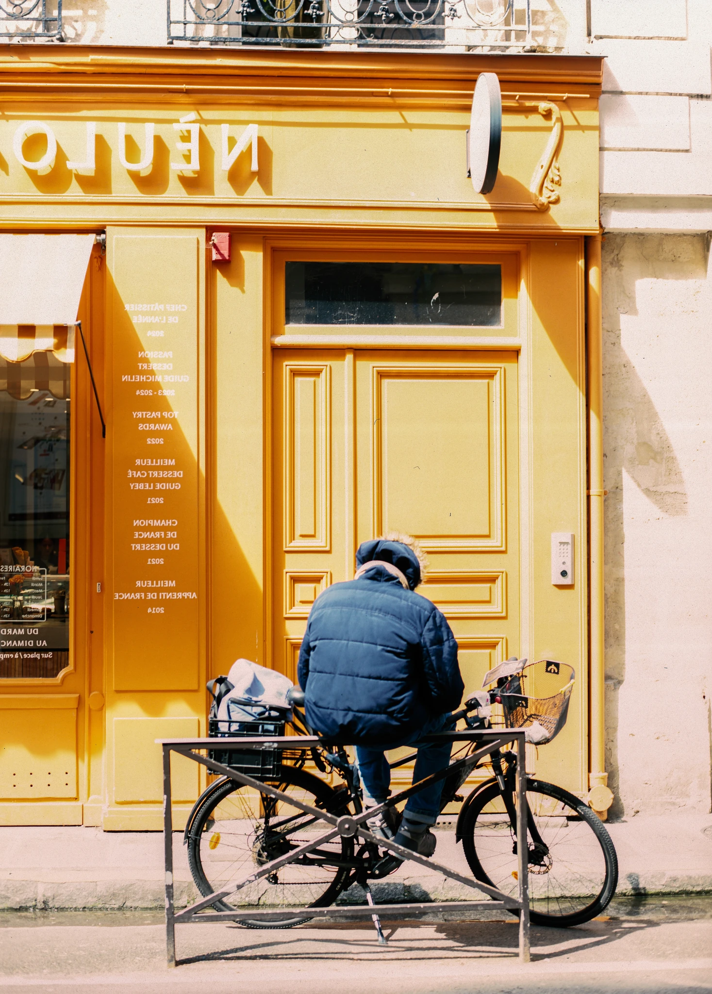 A cyclist passing a bright yellow storefront