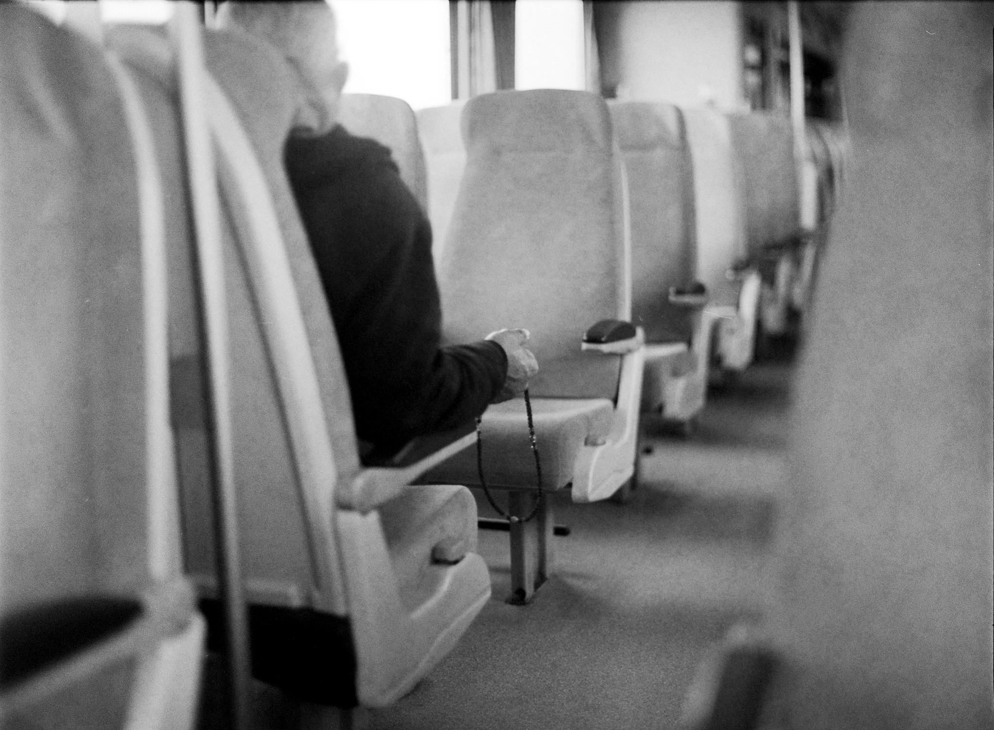 A seated passenger inside a bus in black and white
