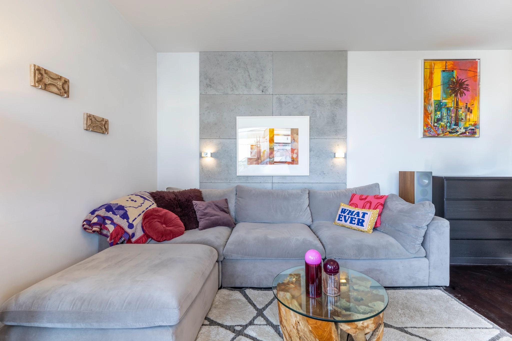 Living room with a grey sectional sofa, glass coffee table and wall art