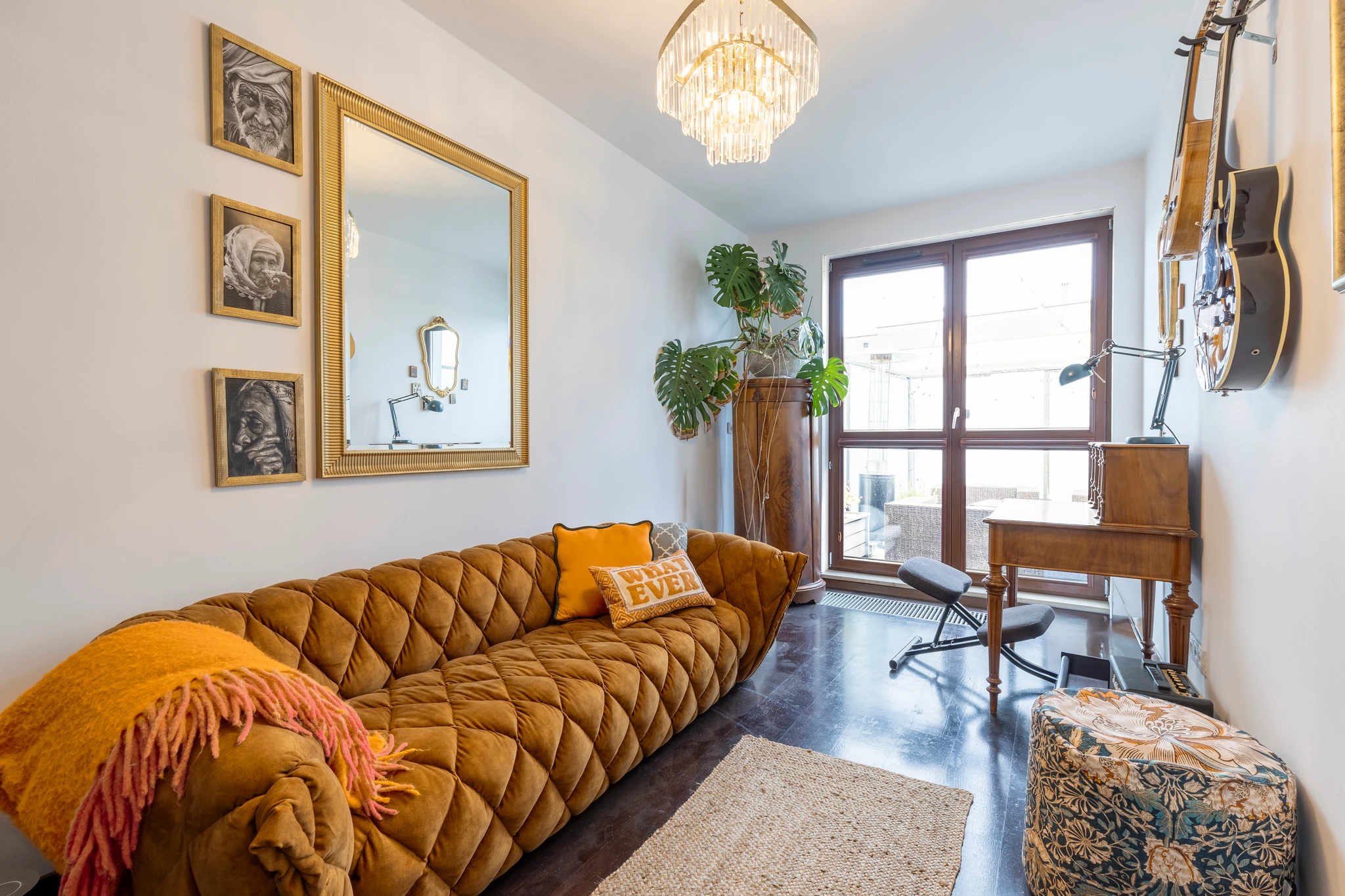 Sitting room with a mustard sofa, framed artwork and balcony doors