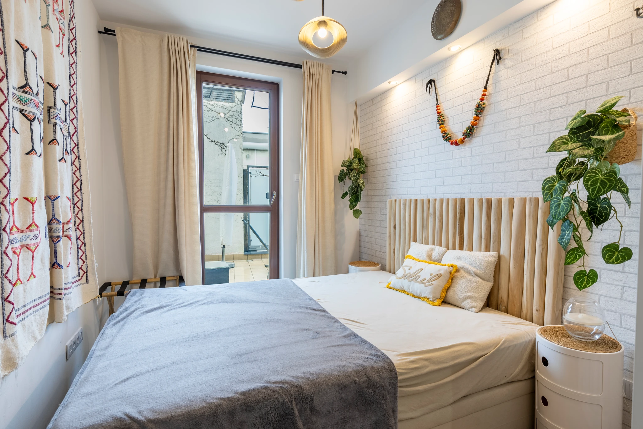 Bedroom with white brick walls, plants and balcony doors