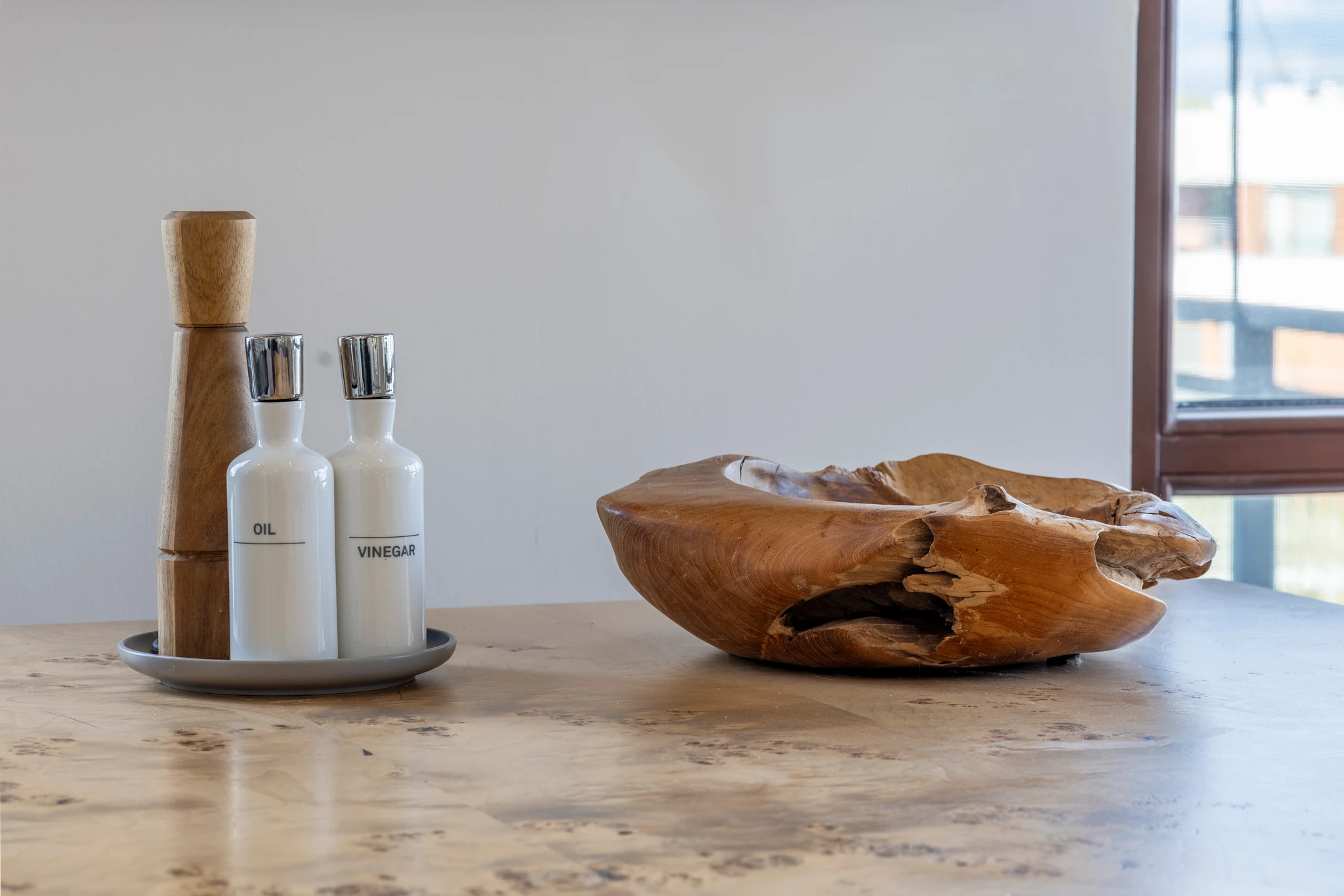 Wooden bowl and oil and vinegar bottles on a marble dining table