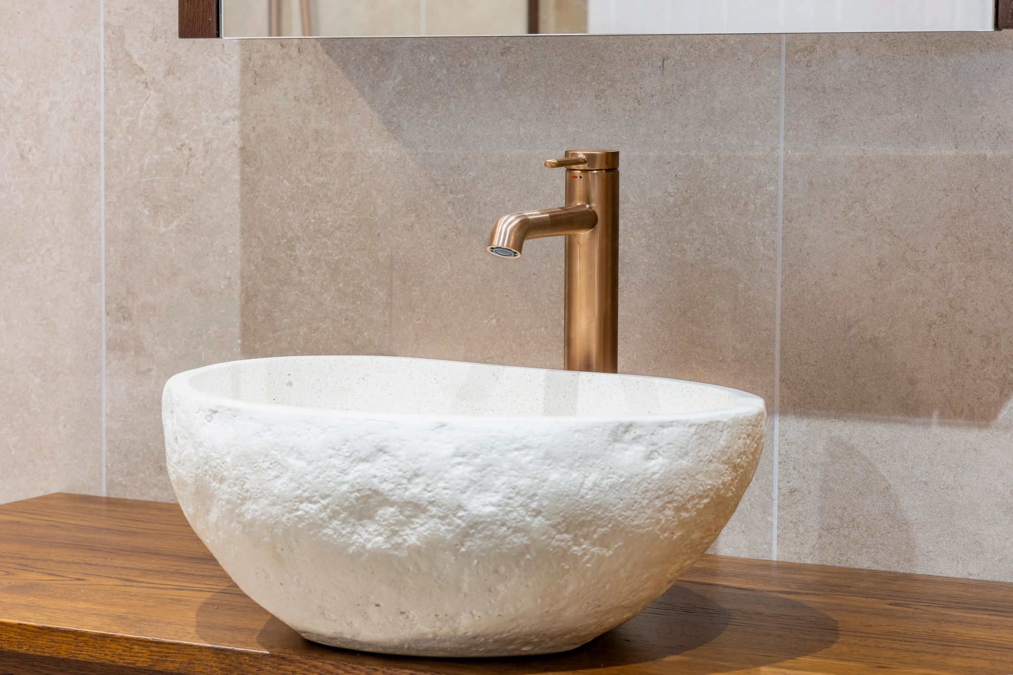 Stone vessel sink with a brass tap and wooden vanity