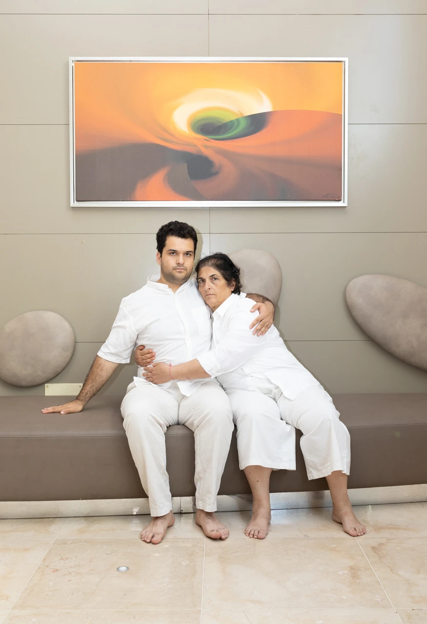 Two people in white seated together beneath a painting